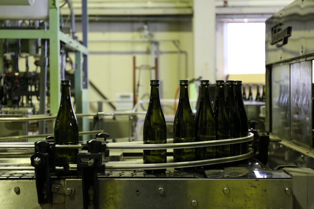 sake bottles lined up for filling in a brewery