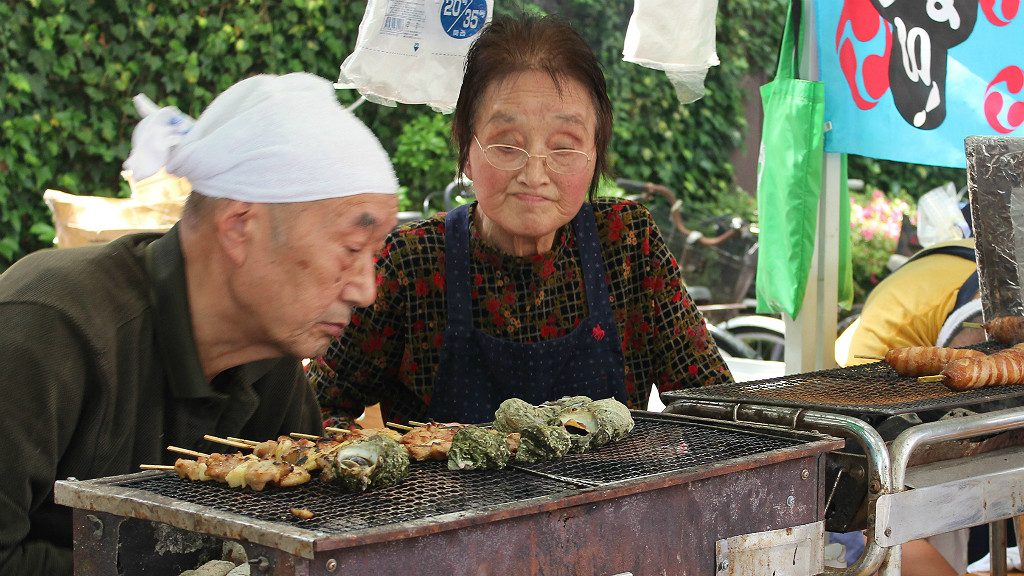 An older couple check their barbecue progress at a food fair in Kanazawa, Japan