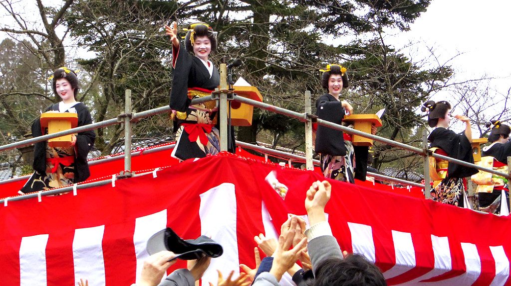 Photo from Kanazawa Tourism, Geisha throwing beans during Setsubun from an elevated platform in front of a shrine