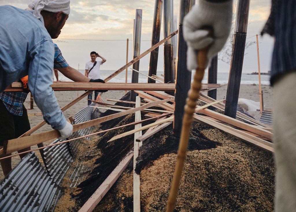 More wood is added to the noyaki fire for a burst of heat as the sun begins to set.