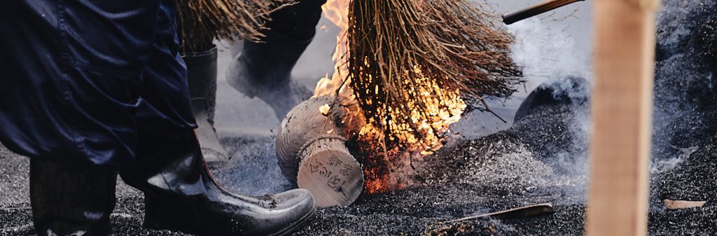 The brooms that brush the burning rice hulls catch fire as they reveal the completed earthenware pottery pieces.