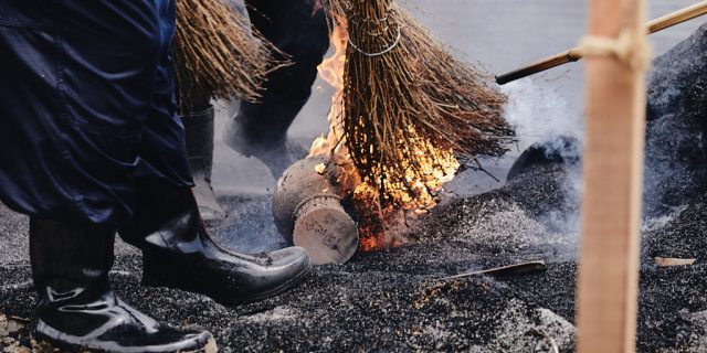 The brooms that brush the burning rice hulls catch fire as they reveal the completed earthenware pottery pieces.