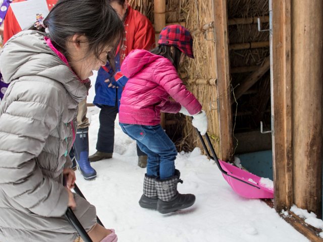 Children shoveling snow into the Himuro Koya in Yuwaku