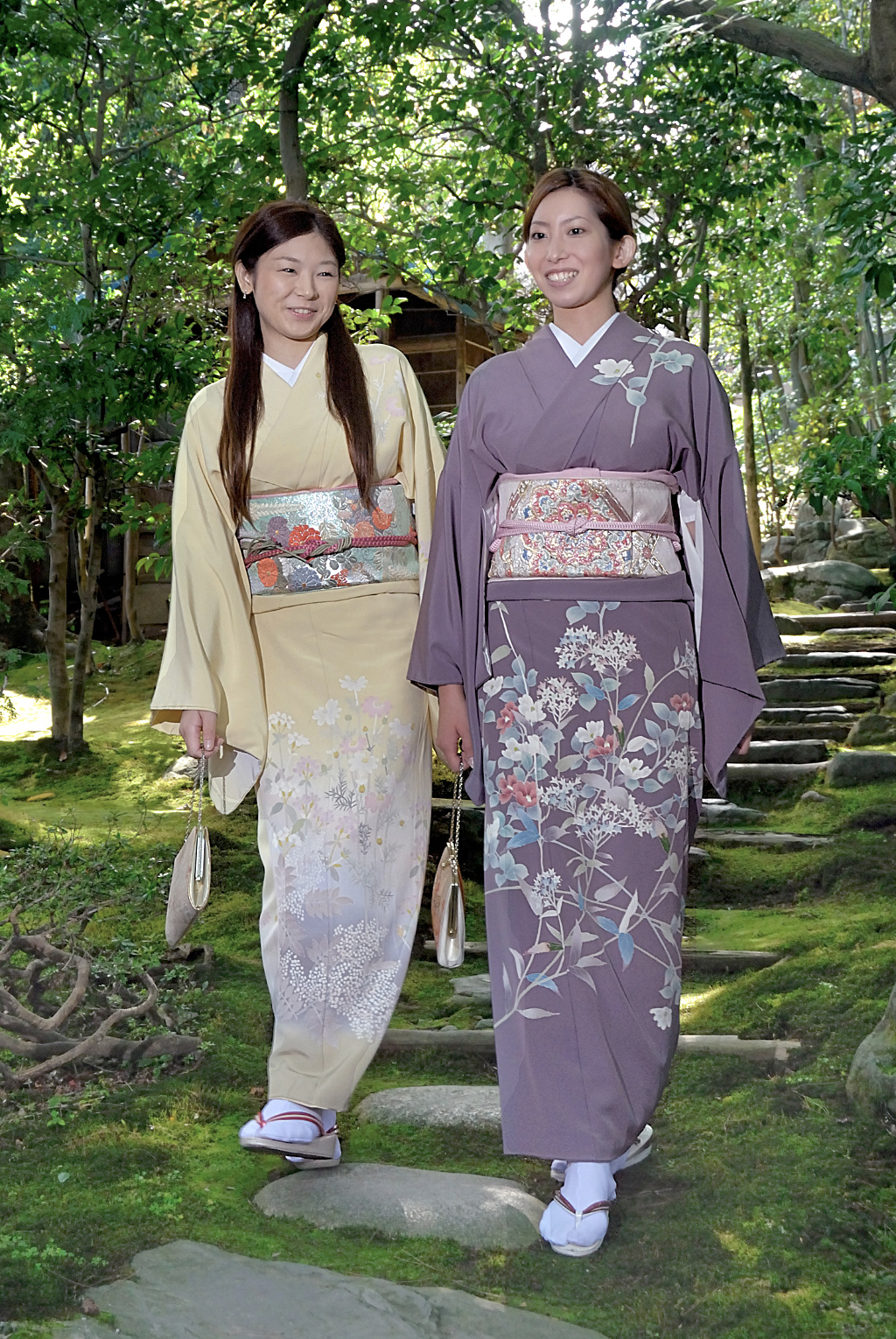 Two women wearing Kaga-yuzen silk kimono and walking through a garden