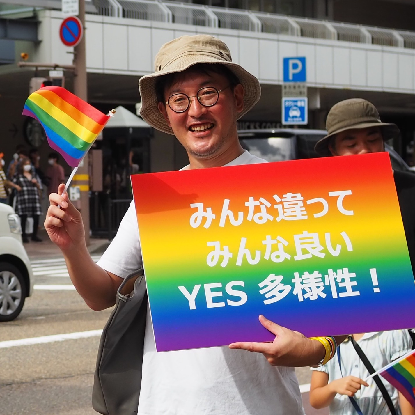 Kaname Inn Tatemachi president, Hiroshi Hosokawa, holding up a sign that translates to "Everyone is different, and everyone is good. 'YES' to diversity!" during the Kanazawa Rainbow Pride Parade
