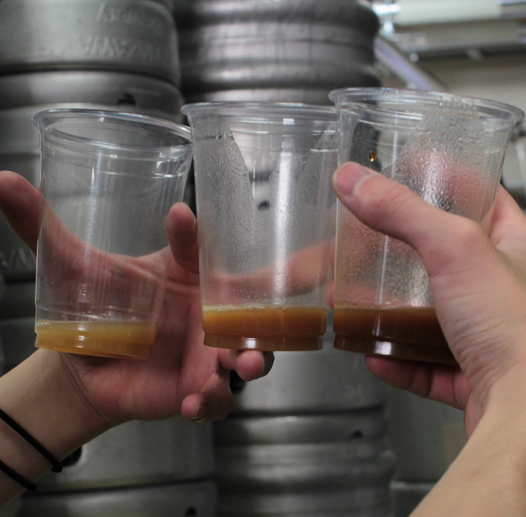 three cups with samples of beer at several stages of the brewing process