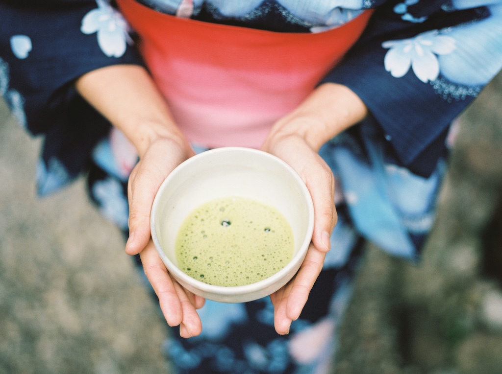 girl in yukata carrying a bowl of matcha